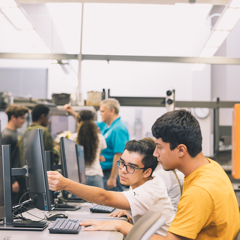 Two male IT students working together to solve an issue.