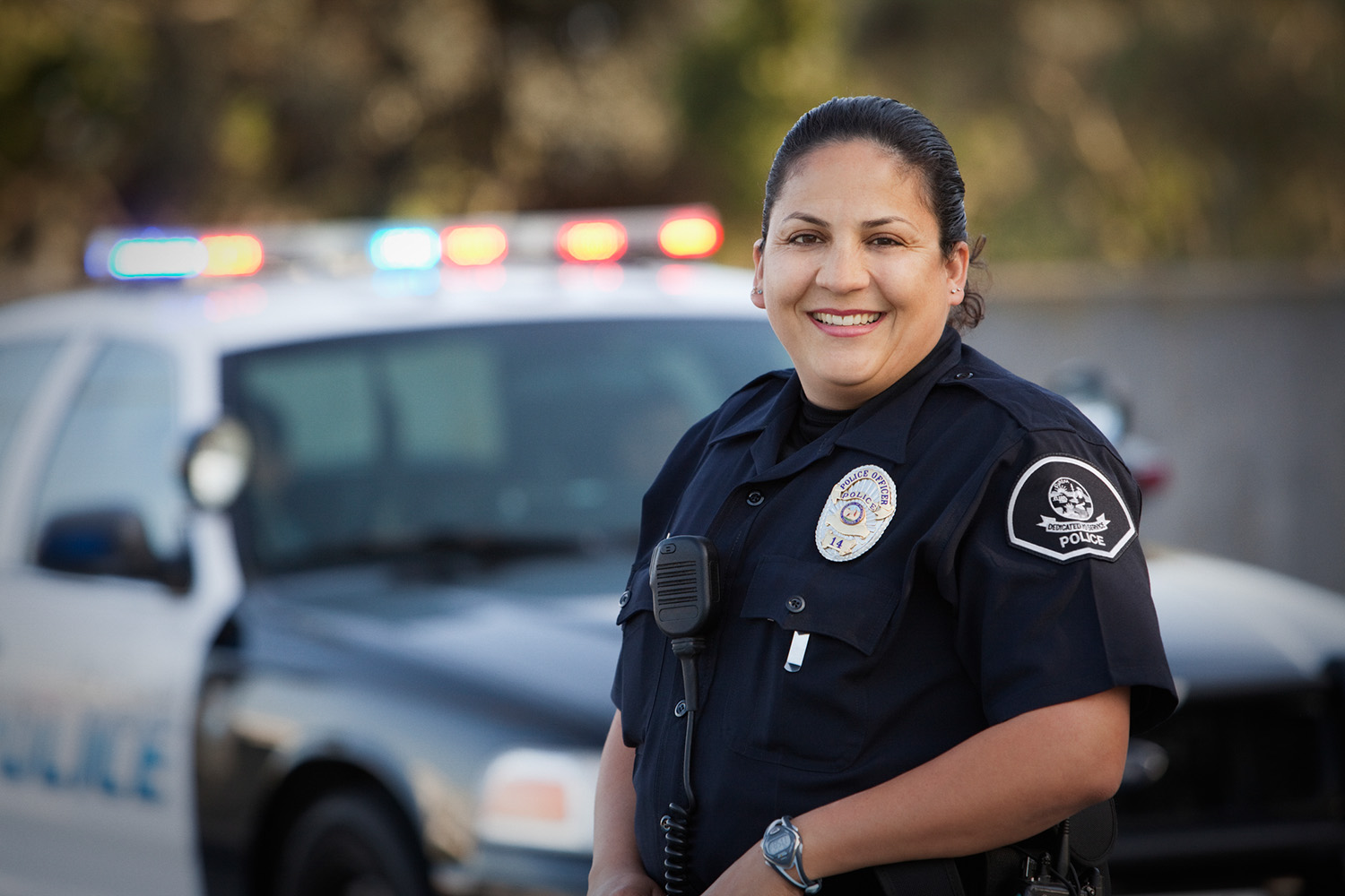 Female police officer standing in front of her squad car smiling